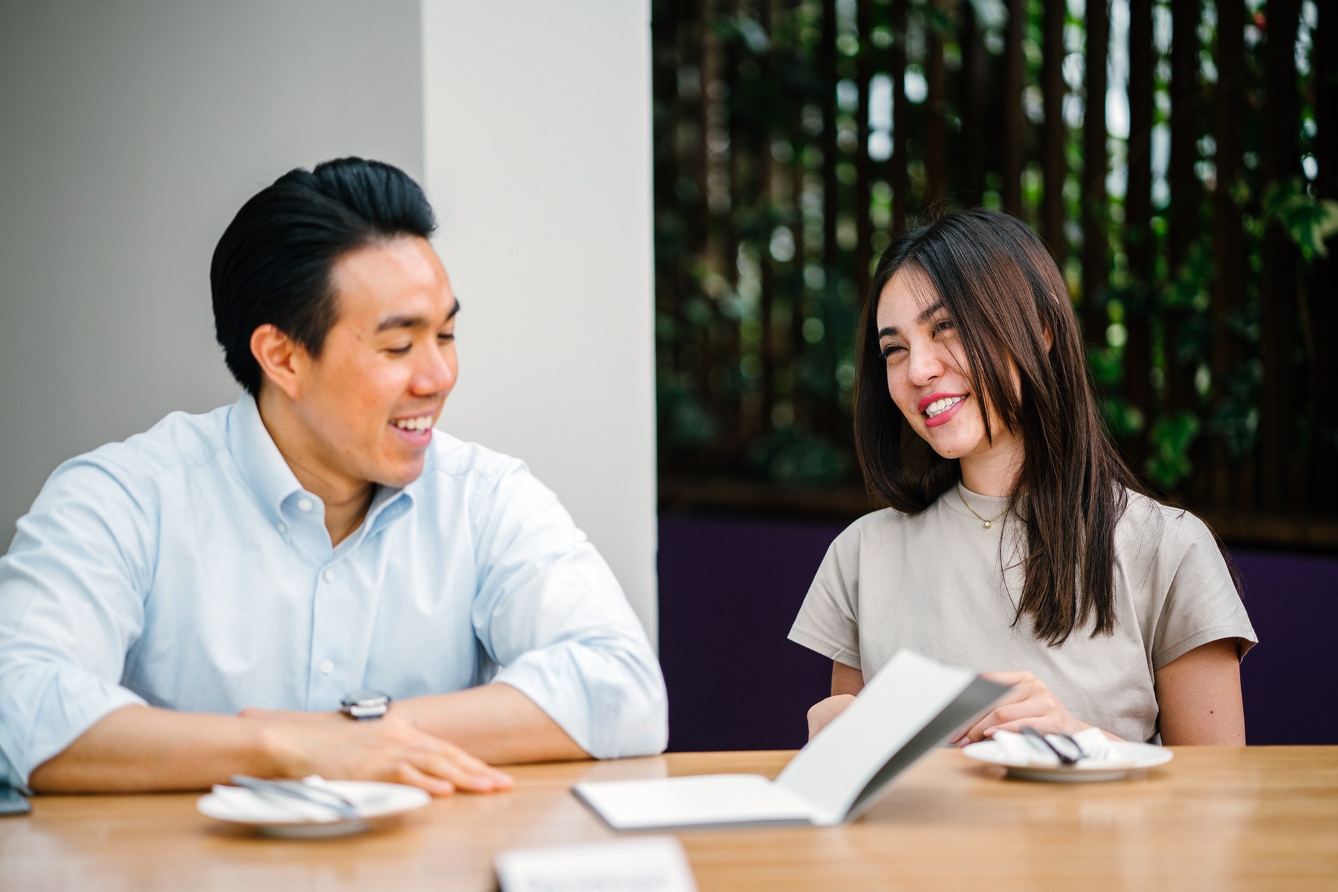 A young asian man and a young asian woman smile in a office meeting