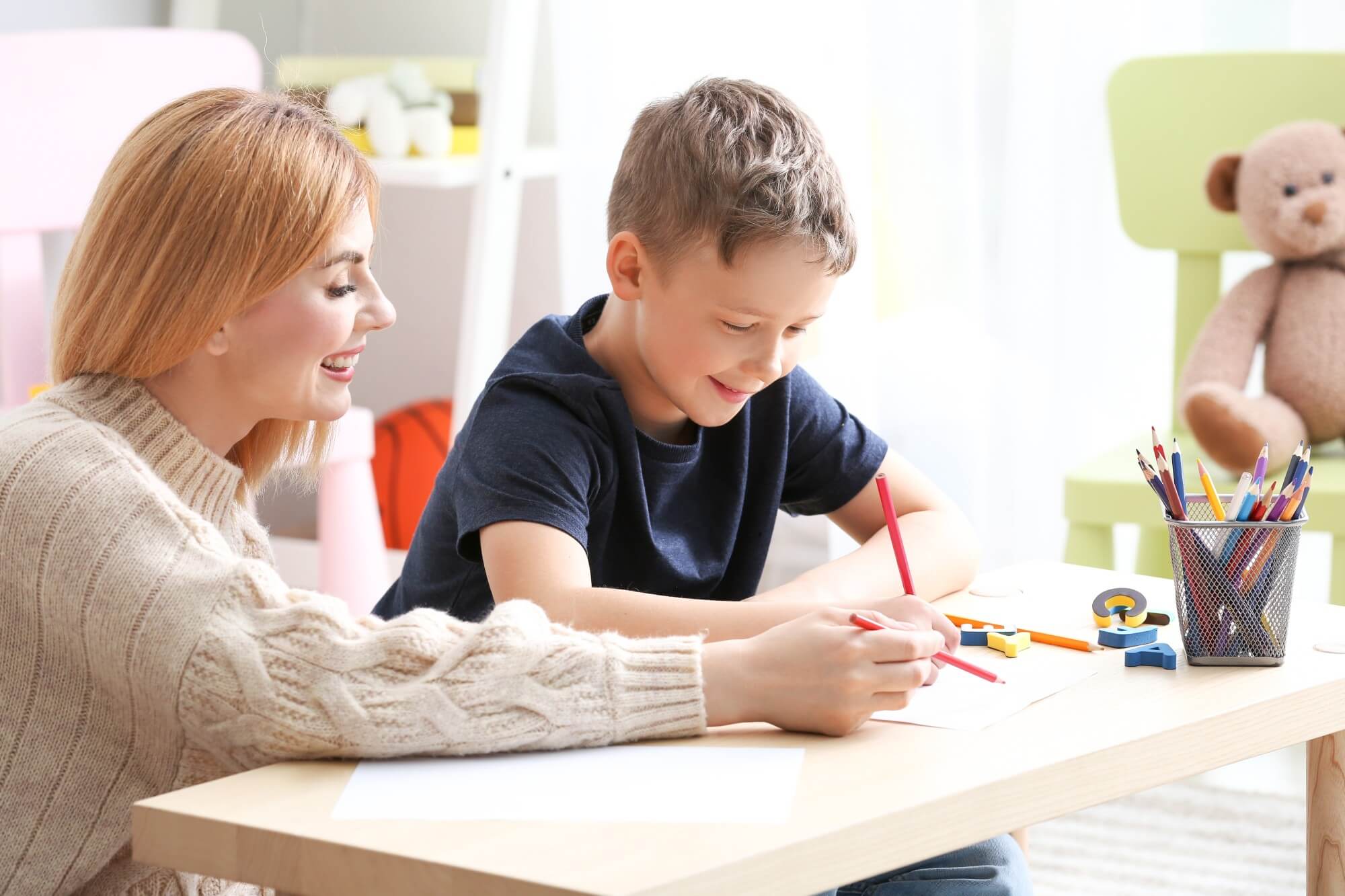 woman help child write in an aba therapy session
