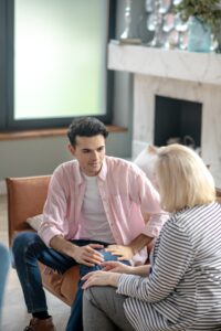 A young man and a woman therapist discuss as they sit on a couch