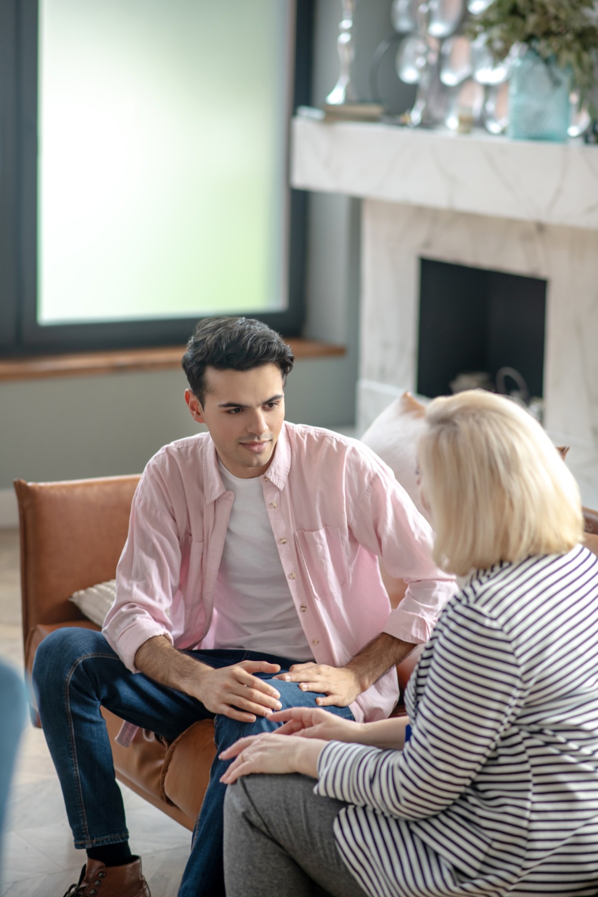 A young man and a woman therapist discuss as they sit on a couch