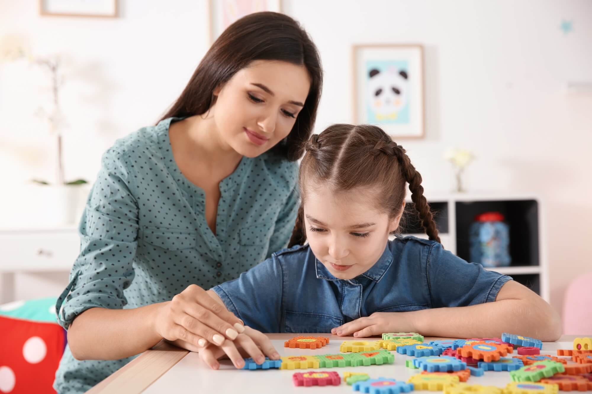 young woman therapist plays and helps young girl with blocks