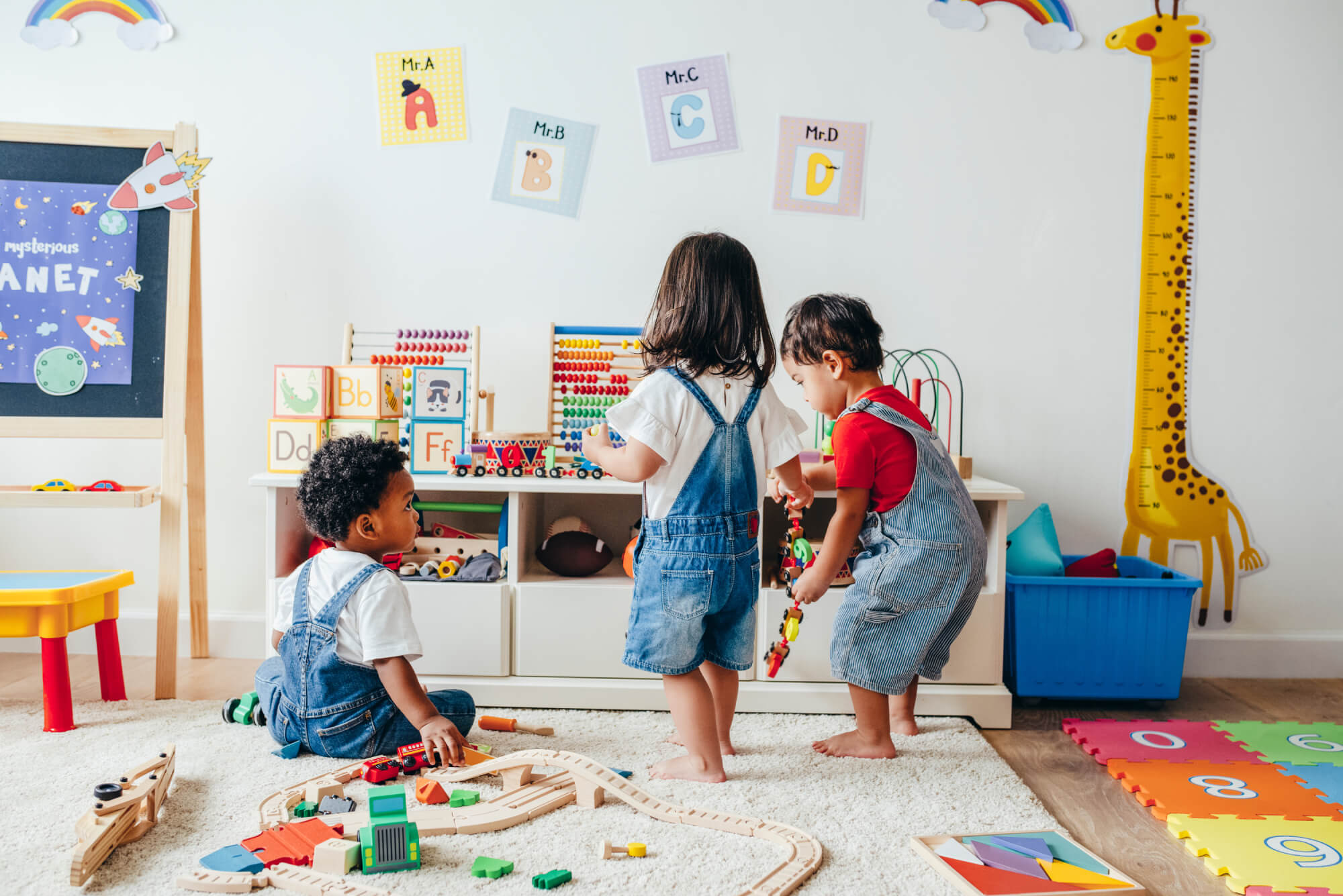 Three small children play together with toys