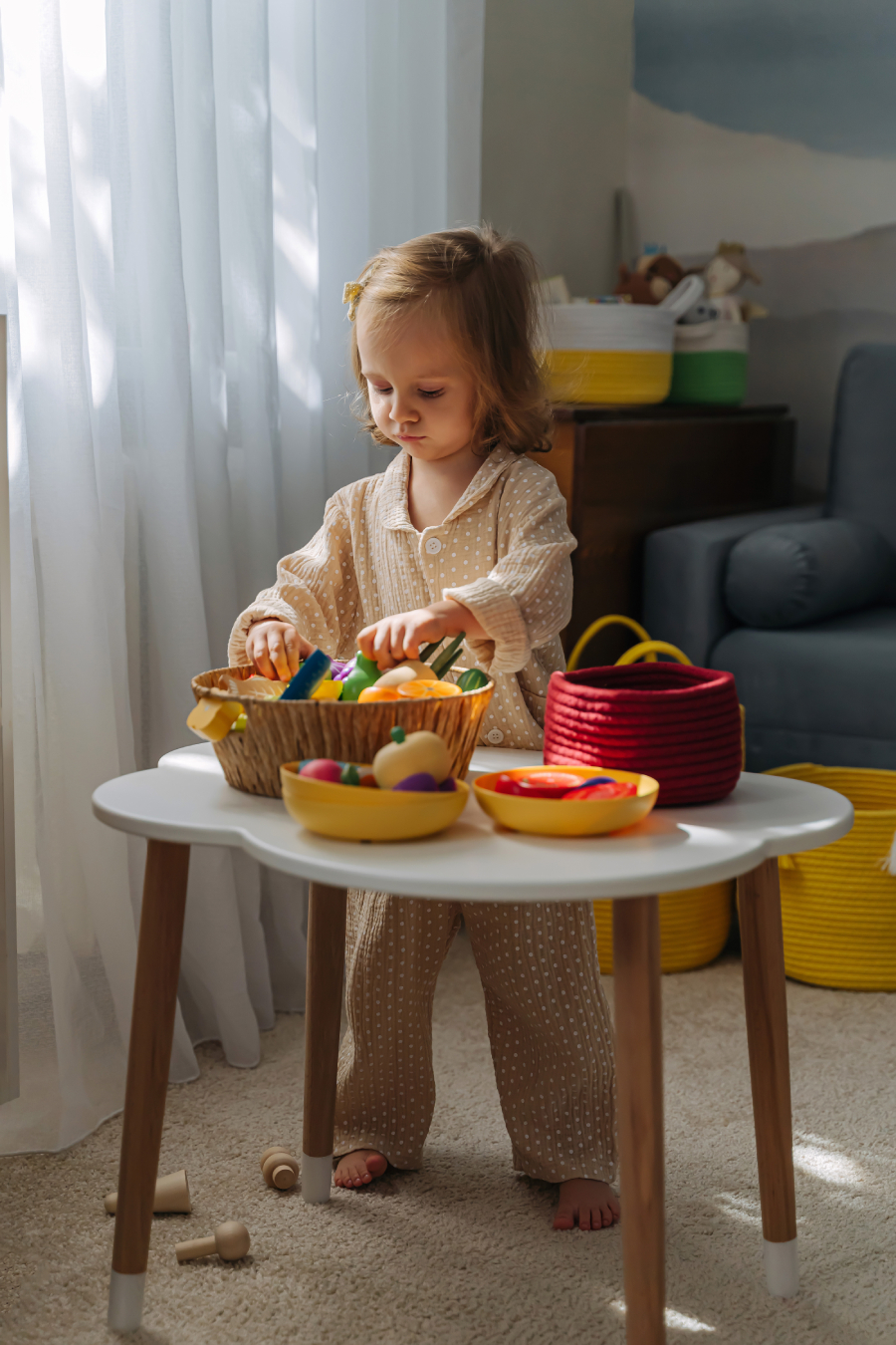A little girl playing with wooden fruits and vegetables on the table in nursery. Educational games, learning through play. Developing Montessori toddlers activities.