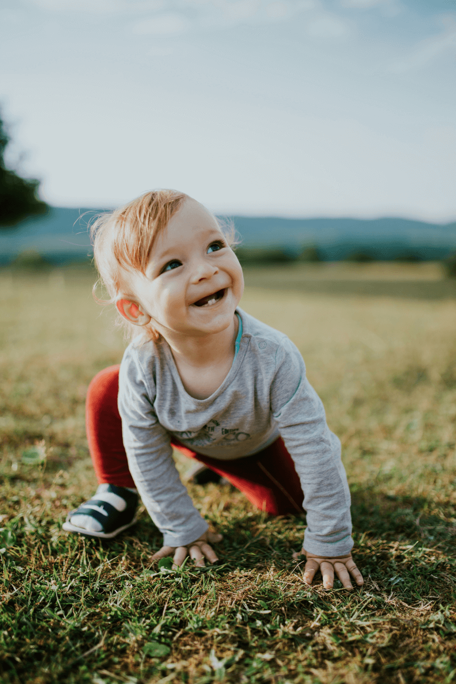 happy baby boy playing outside on the grass smiling
