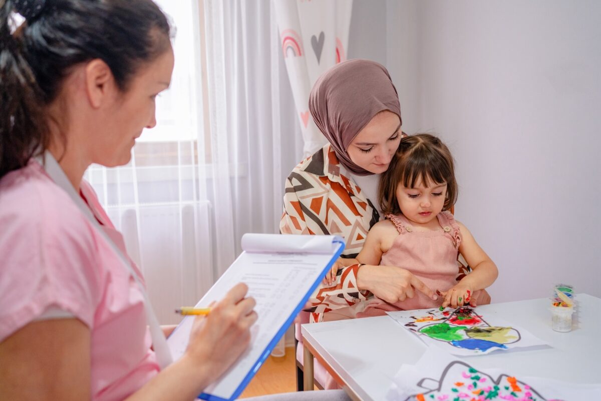 A child psychologist Play therapist colors with a girl and her mom during a play therapy