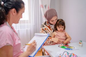 A child psychologist Play therapist colors with a girl and her mom during a play therapy
