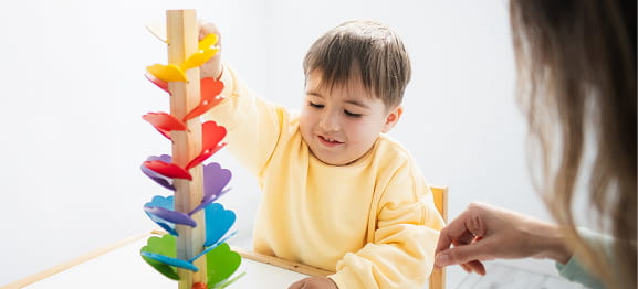 Child stacking colorful wooden toy with adult guidance
