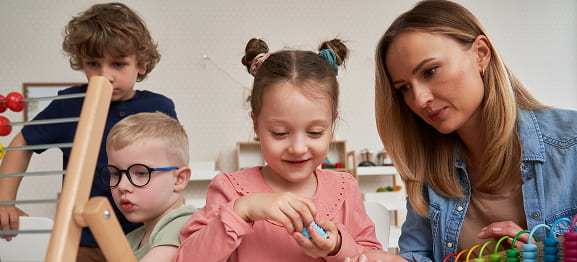 Teacher guiding children with educational toys in classroom