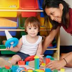 toddler girl with woman therapist playing with blocks