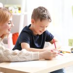 woman help child write in an aba therapy session