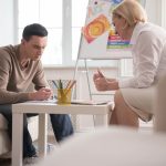 A young man sits with a woman therapist in a counseling session