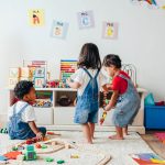 Three small children play together with toys